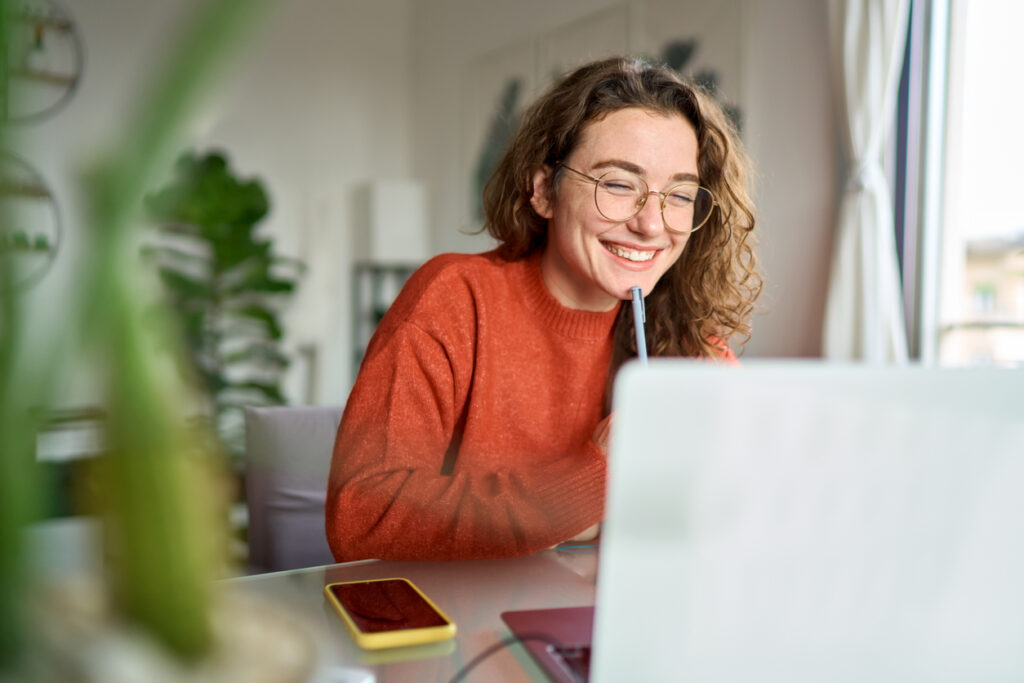 Mulher sorrindo ao estudar com seu notebook